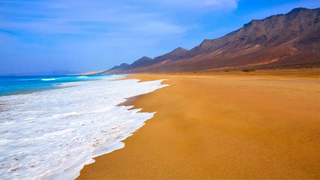 Cofete Beach Fuerteventura with teh blue swa and mountain backdrop